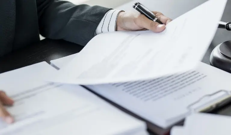 Person reviewing documents with a gavel on the desk, implying a legal setting.