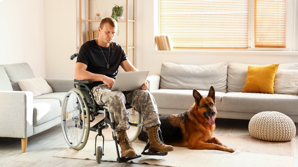 veteran in wheelchair with laptop and his dog
