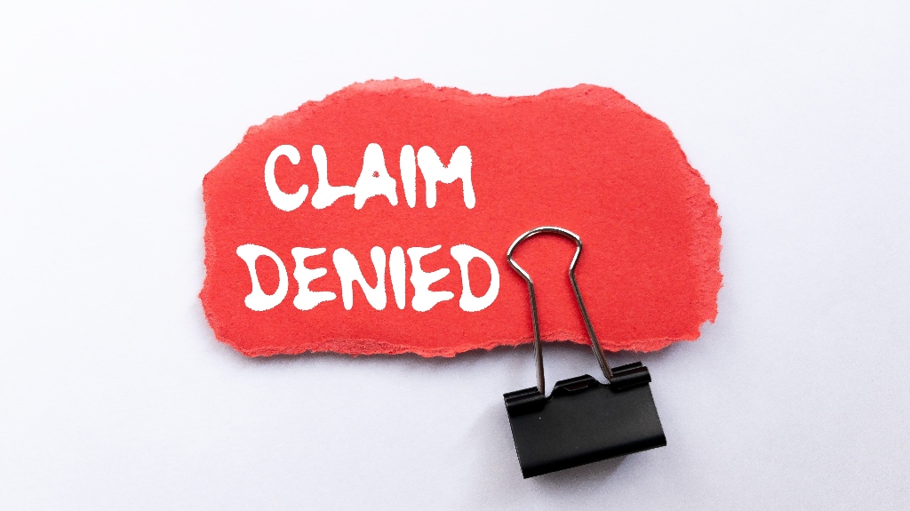 Claim denied message written on ripped torn red paper piece